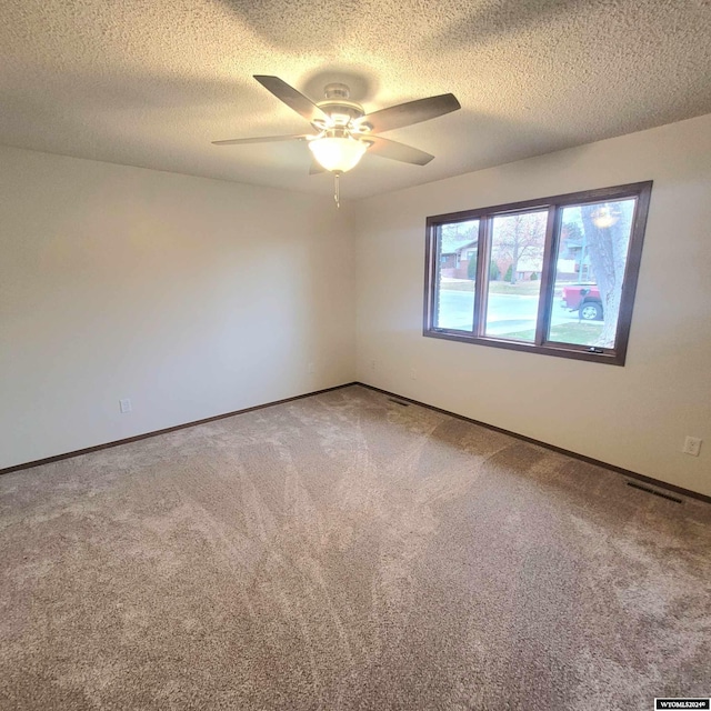 spare room featuring carpet flooring, ceiling fan, and a textured ceiling