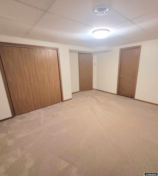 unfurnished bedroom with a paneled ceiling and light carpet