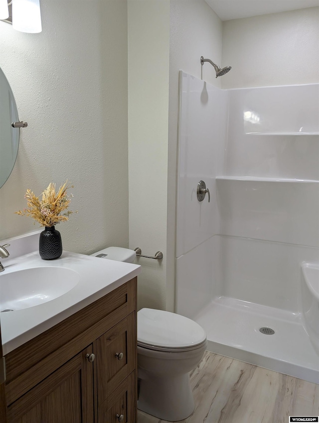 bathroom featuring hardwood / wood-style floors, toilet, a shower, and vanity