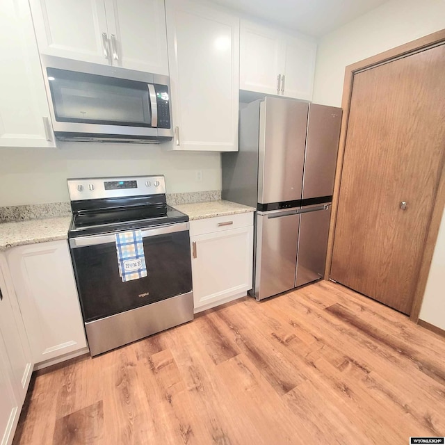 kitchen featuring light stone countertops, appliances with stainless steel finishes, light hardwood / wood-style flooring, and white cabinetry