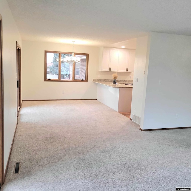 unfurnished living room with a notable chandelier and light colored carpet