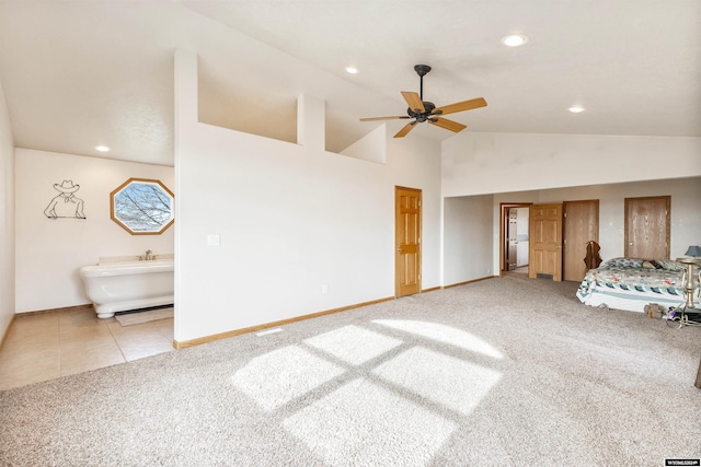 unfurnished bedroom with ensuite bathroom, ceiling fan, light colored carpet, and high vaulted ceiling