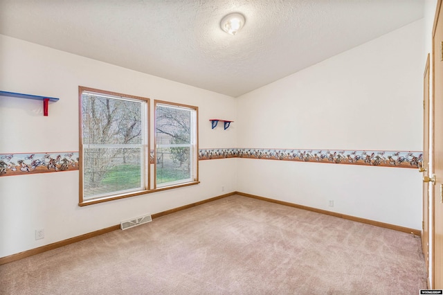 carpeted empty room featuring vaulted ceiling and a textured ceiling