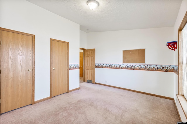 unfurnished bedroom with a textured ceiling, light colored carpet, and lofted ceiling