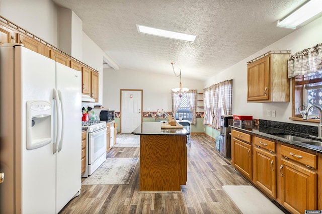 kitchen featuring hardwood / wood-style floors, lofted ceiling, white appliances, sink, and a kitchen island