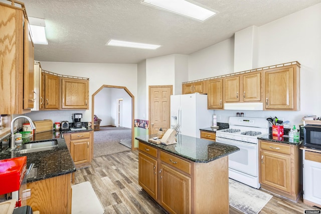 kitchen with white appliances, vaulted ceiling, light wood-type flooring, a textured ceiling, and a kitchen island