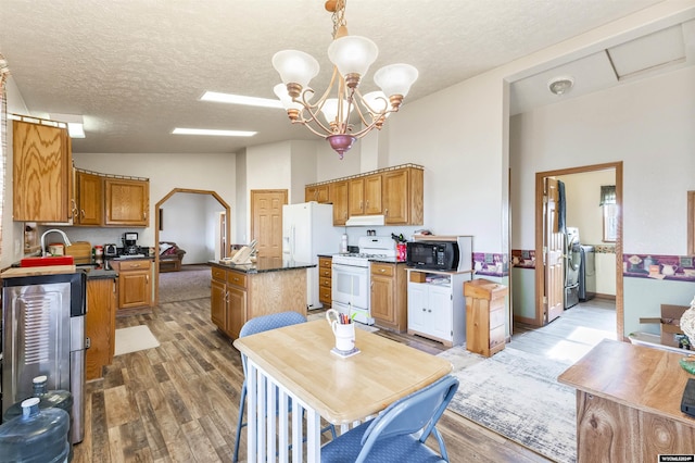 kitchen featuring pendant lighting, hardwood / wood-style floors, white appliances, an inviting chandelier, and a kitchen island