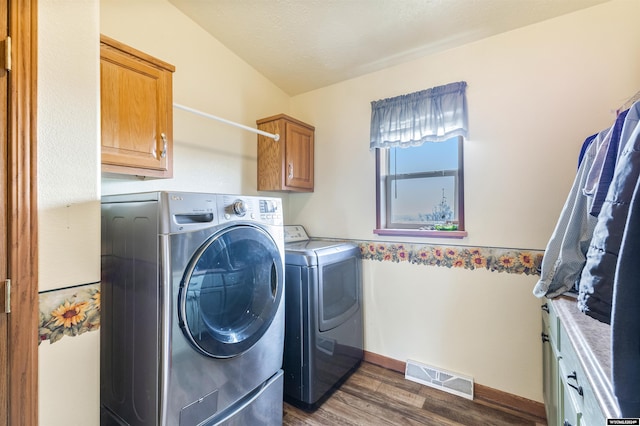 laundry area featuring cabinets, dark hardwood / wood-style flooring, and washing machine and clothes dryer