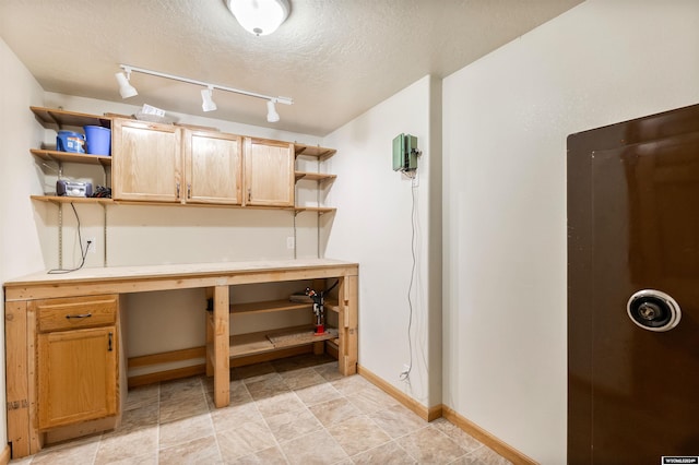 basement with a textured ceiling and track lighting