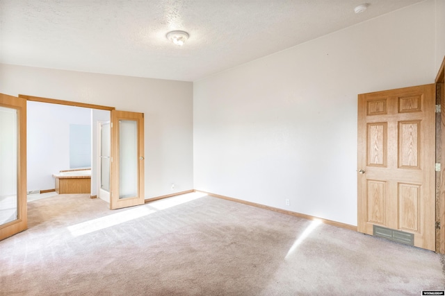 unfurnished bedroom featuring ensuite bathroom, light colored carpet, lofted ceiling, and a textured ceiling