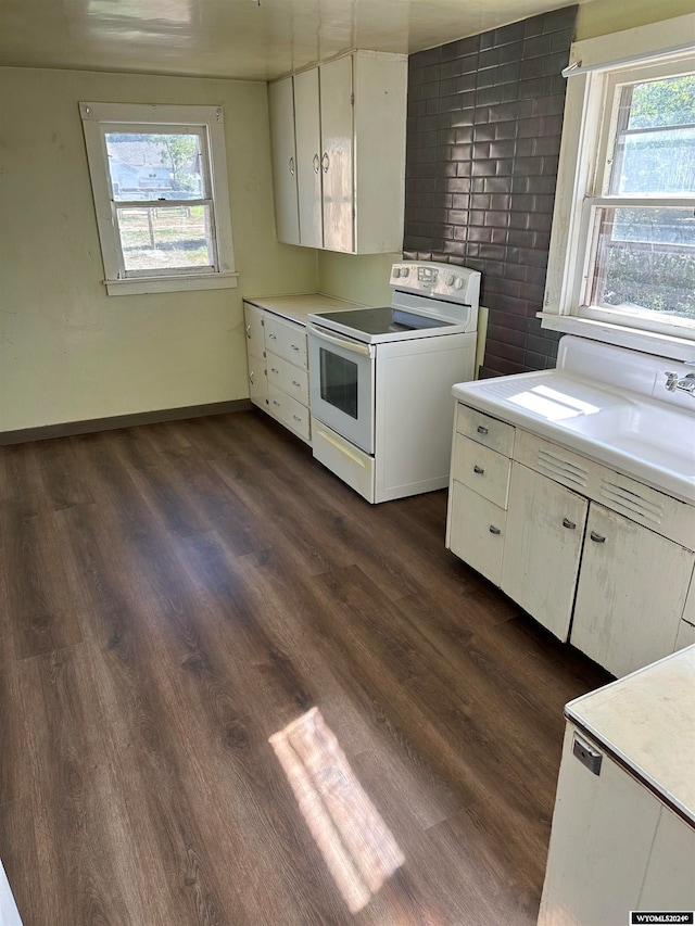 kitchen with electric range, plenty of natural light, dark hardwood / wood-style flooring, and white cabinets