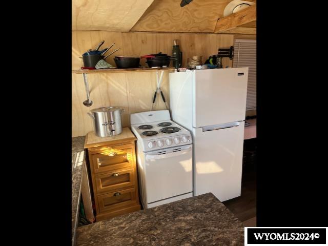 kitchen featuring white appliances and wooden walls