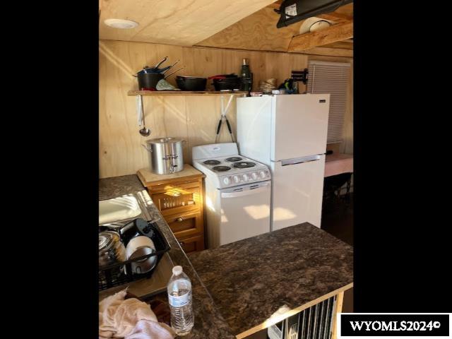 kitchen with wood walls, white appliances, and kitchen peninsula