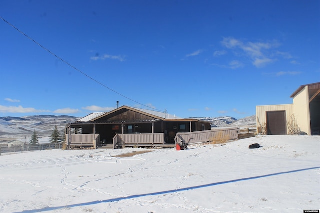 snow covered house featuring a mountain view and a porch