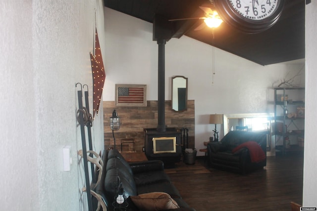 living room with ceiling fan, dark wood-type flooring, vaulted ceiling with beams, a wood stove, and wood walls