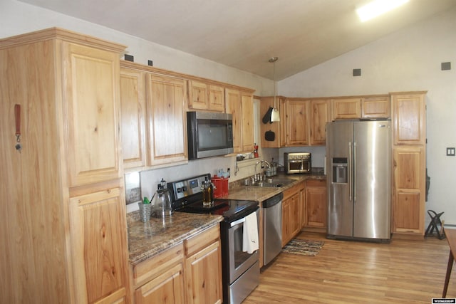 kitchen featuring sink, stainless steel appliances, dark stone counters, lofted ceiling, and light wood-type flooring