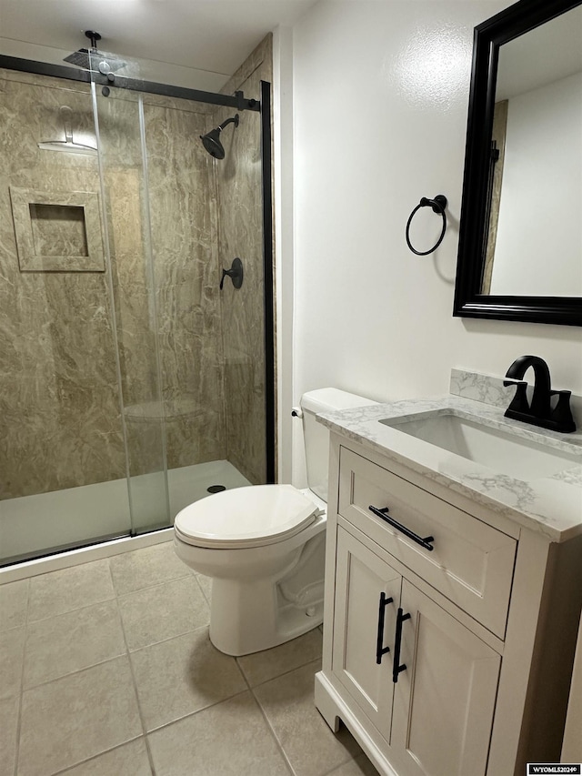 bathroom featuring tile patterned flooring, vanity, a shower with shower door, and toilet