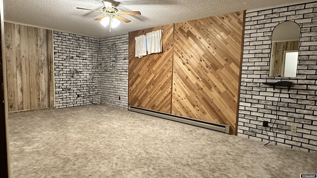 carpeted spare room with brick wall, a textured ceiling, a baseboard heating unit, and wood walls