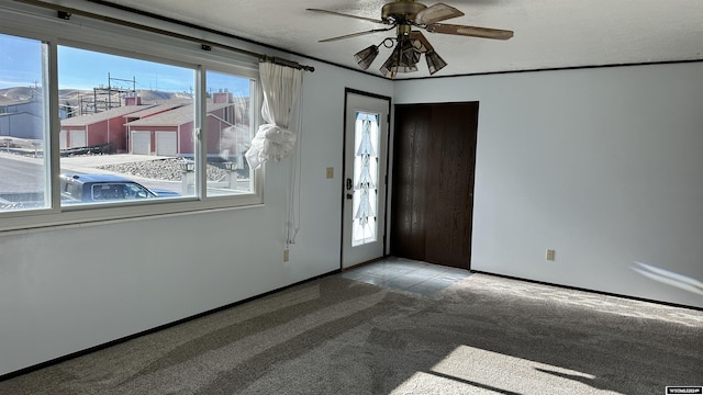 carpeted foyer featuring a textured ceiling and ceiling fan