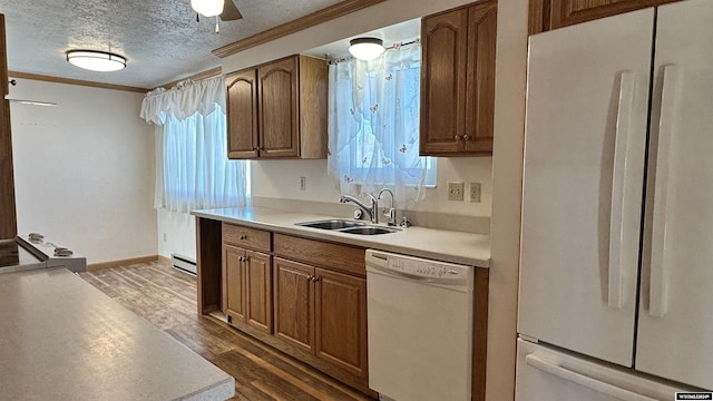 kitchen with ornamental molding, white appliances, a textured ceiling, dark wood-type flooring, and sink