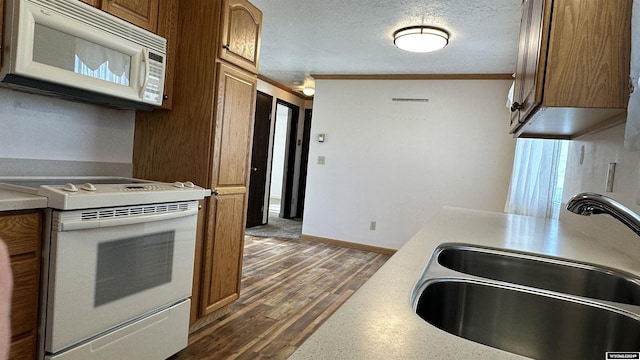 kitchen with ornamental molding, a textured ceiling, white appliances, sink, and dark hardwood / wood-style floors