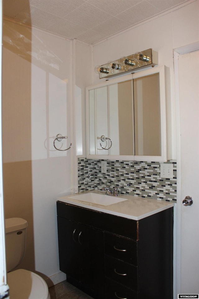 bathroom featuring vanity, toilet, and tasteful backsplash