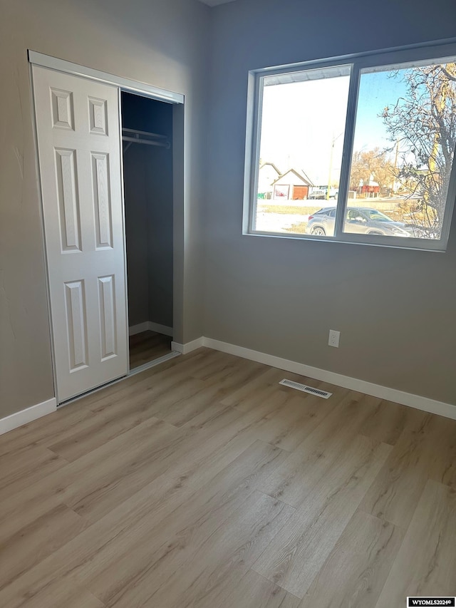 unfurnished bedroom with light hardwood / wood-style flooring and a closet