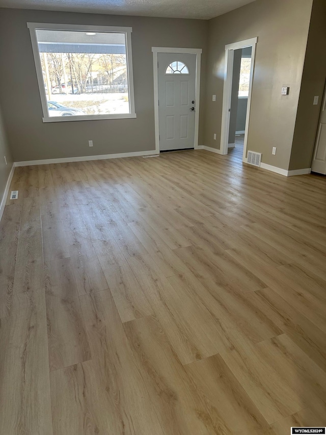 foyer entrance featuring a textured ceiling and light hardwood / wood-style flooring