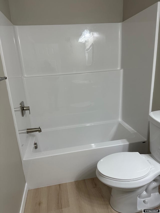 bathroom with wood-type flooring,  shower combination, and toilet