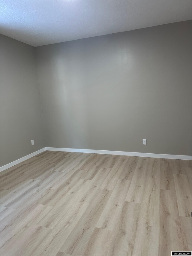 unfurnished room with a textured ceiling and light hardwood / wood-style flooring