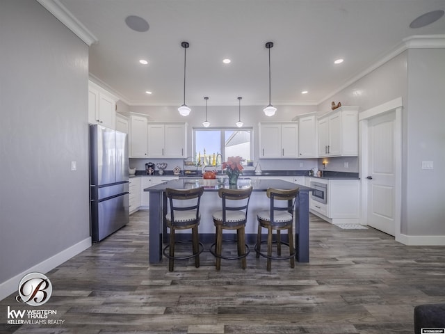 kitchen featuring stainless steel appliances, white cabinets, dark hardwood / wood-style floors, a kitchen island, and ornamental molding