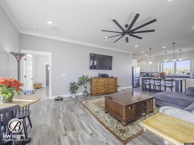 living room with crown molding, sink, ceiling fan, and light hardwood / wood-style floors