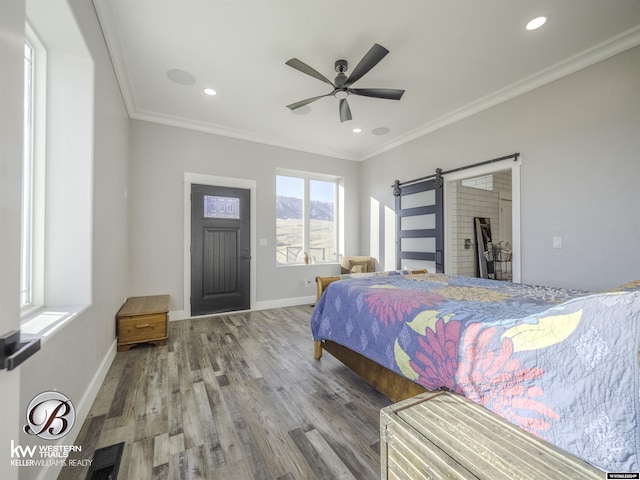 bedroom featuring hardwood / wood-style floors, a barn door, ceiling fan, and crown molding