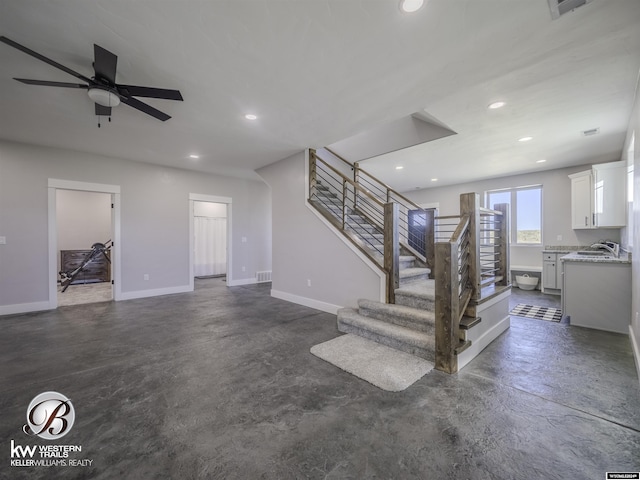 unfurnished living room featuring ceiling fan and sink