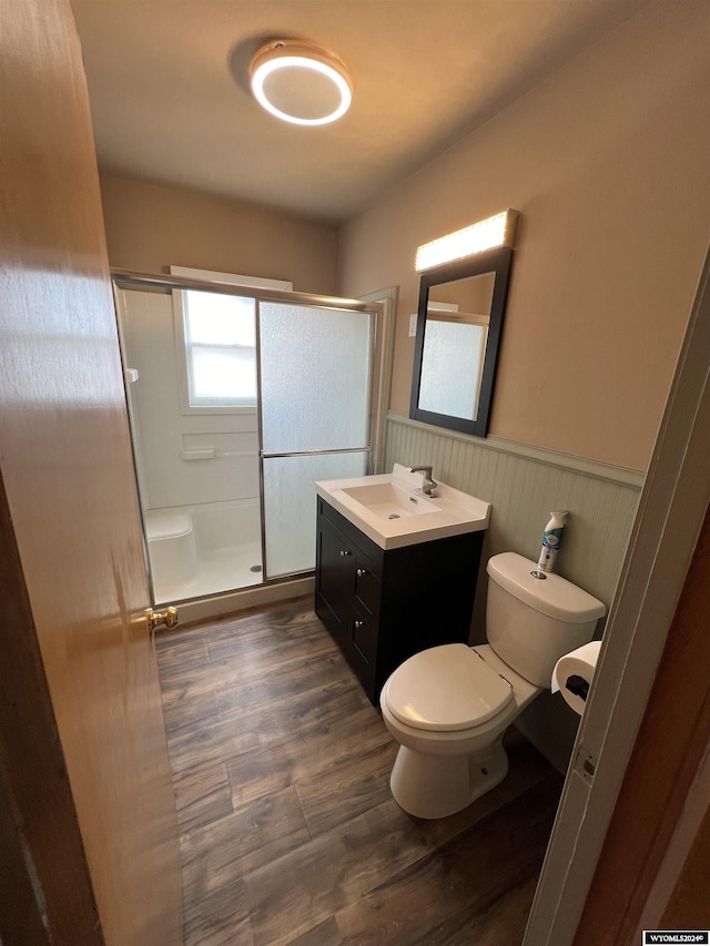 610 Charles St, Douglas, WY 82633 - bathroom featuring a wainscoted wall, a stall shower, vanity, toilet, and wood finished floors