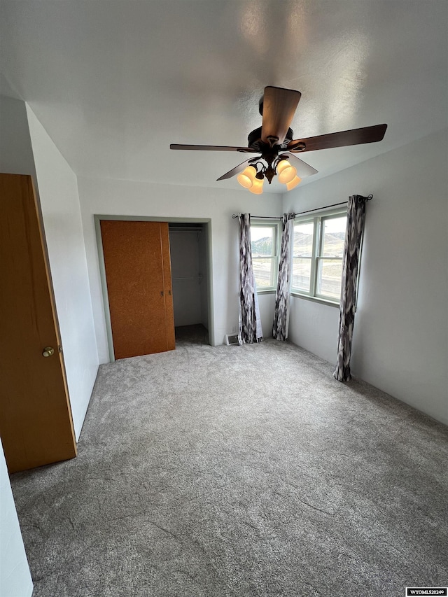 unfurnished bedroom featuring carpet, ceiling fan, and a closet