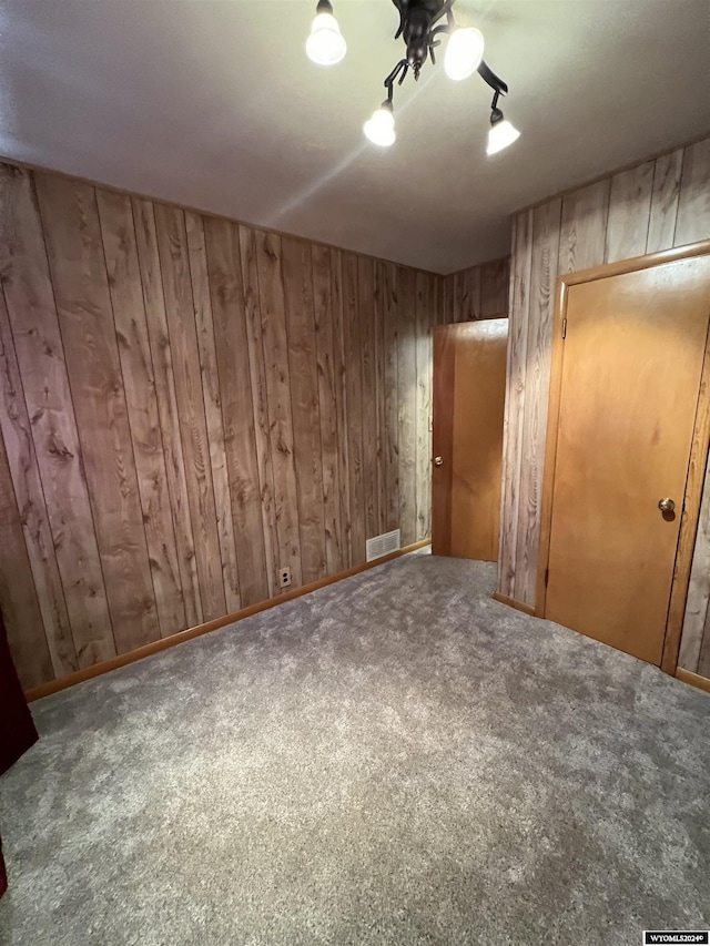 unfurnished bedroom featuring ceiling fan, carpet floors, and wooden walls