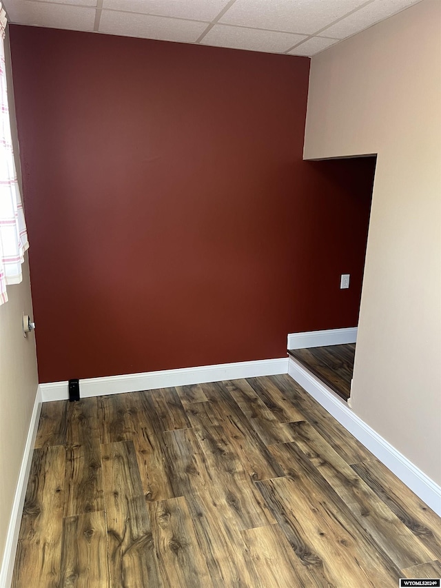 unfurnished room with a drop ceiling and dark wood-type flooring