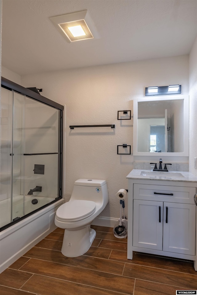 full bathroom featuring wood-type flooring, vanity, toilet, and bath / shower combo with glass door