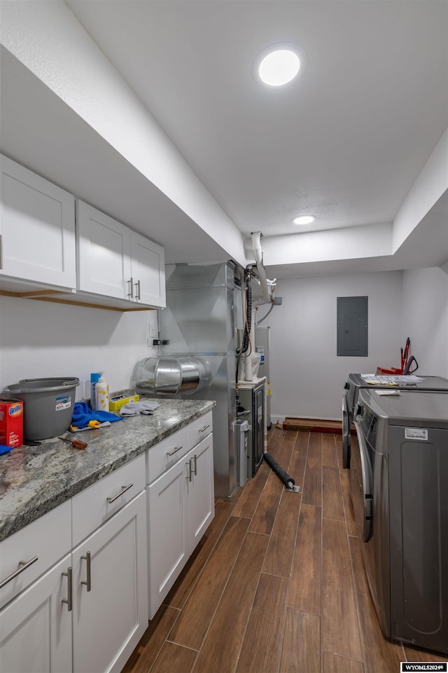 kitchen with dark wood-type flooring, electric panel, white cabinets, washer and dryer, and light stone countertops