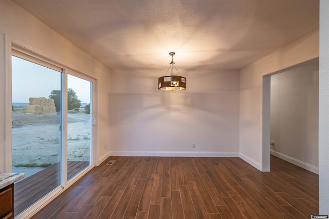 empty room featuring a textured ceiling and dark wood-type flooring