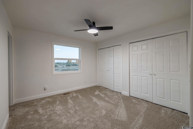 unfurnished bedroom with light carpet, ceiling fan, and multiple closets