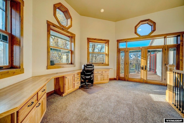 unfurnished office featuring light carpet, french doors, and built in desk