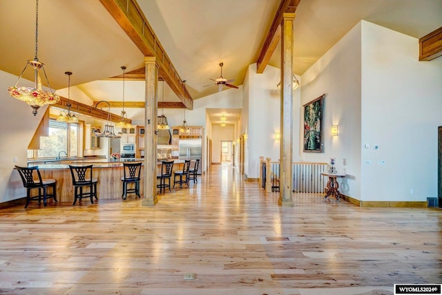 kitchen with beam ceiling, ceiling fan, hanging light fixtures, light hardwood / wood-style flooring, and kitchen peninsula