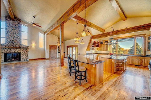 kitchen featuring a center island, light hardwood / wood-style flooring, pendant lighting, a breakfast bar area, and a fireplace