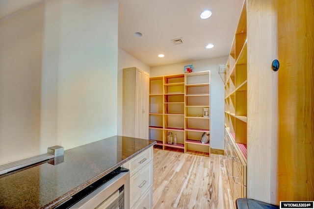 kitchen featuring white cabinetry, dark stone countertops, and light wood-type flooring