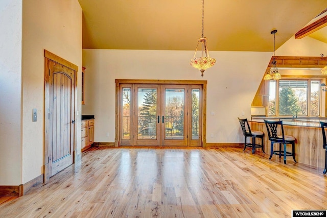 foyer with vaulted ceiling with beams, light wood-type flooring, a wealth of natural light, and french doors