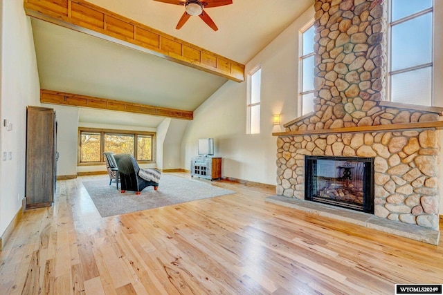 unfurnished living room with high vaulted ceiling, a stone fireplace, light hardwood / wood-style flooring, ceiling fan, and beamed ceiling