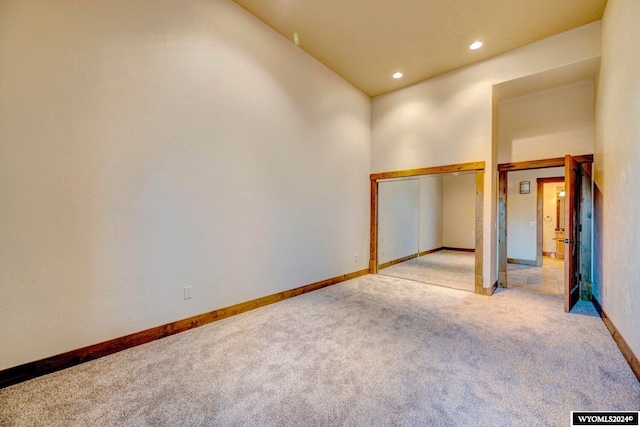 empty room featuring a towering ceiling and light colored carpet