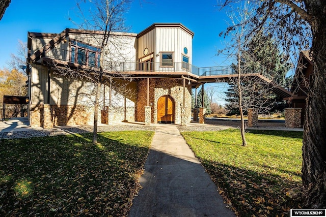 view of front of house featuring a balcony and a front lawn